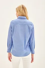 Camisa celeste de manga larga con volados en el frente y cuello clásico.