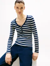 Remera de manga larga a rayas horizontales blancas y azules, con cuello Henley y botones dorados.