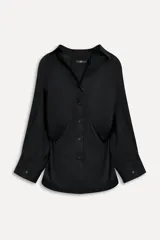 Camisa negra de algodón con cuello solapa, manga larga tipo murciélago con puños abotonados, hombros caídos, bolsillo de parche en el pecho, pinzas en la espalda y cierre frontal con botones.