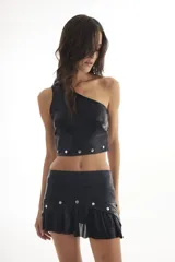 Top negro de un solo hombro confeccionado en tela acanalada con brillo y apliques de tachuelas.