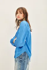 Camisa blanca de poliéster con cuello mao y mangas largas con frunces en hombros, mangas y espalda.