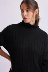 Vestido largo negro de punto canale con cuello alto y mangas largas.