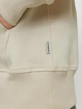 Hoodie tipo canguro color beige claro, de manga larga con capucha y fit regular. Cuenta con un bolsillo y estampado de goma con la palabra "Originals".