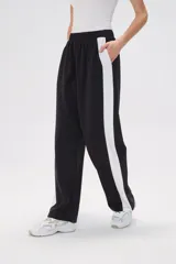 Pantalón de jogging negro con cintura elástica, corte holgado y una franja vertical blanca a lo largo de la pierna.