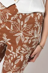 Pantalón de corte recto color marrón con bordado floral blanco.