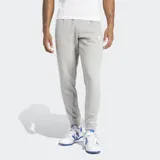 Pantalón de jogging Adidas Adicolor 3 Rayas, color gris con las tres rayas blancas a los costados. Cuenta con puños acanalados, bolsillos laterales con cierre, cintura elástica con cordón de ajuste y logo bordado.