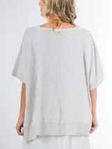 Blusa tipo poncho confeccionada en lino italiano color gris claro, con escote en V y calce amplio.
