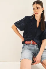 Camisa azul con bordado de flores a tono, de corte amplio, mangas al codo, cuello redondo y abertura en V.