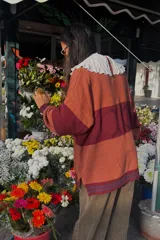 Cárdigan tejido a rayas horizontales en tonos naranja y borgoña, con cuello babero blanco de encaje.