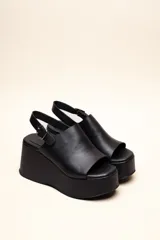 Sandalias con plataforma color marrón, con capellada envolvente, pulsera trasera ajustable y hebilla metálica.