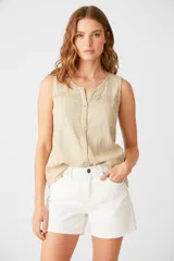 Musculosa color beige claro, sin mangas, con cuello redondo y detalle de encaje en la parte superior.