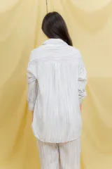 Conjunto color beige compuesto por una camisa oversize de manga larga con botones frontales y bolsillo en el pecho, y un pantalón amplio con cintura elástica.
