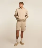 Saco beige de algodón y poliéster con capucha, bolsillo canguro, manga larga ajustada con estampa de llamas lateral, bajo ajustado y estampa lettering localizada.