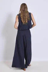 Blusa sin mangas color azul marino, con cuello redondo y detalle de tablas verticales en el frente. Corte corto con terminación fruncida y lazos ajustables en el escote.