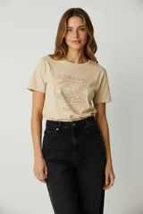 Remera color beige con estampado de texto "Romantic Whispers" y dibujo de personajes de caricatura.