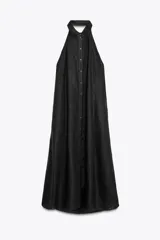 Vestido midi negro de lino, con cuello halter, hombros descubiertos, espalda descubierta, cierre frontal con botones y bajo asimétrico.