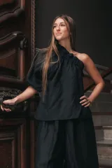 Blusa negra de lino con un solo hombro, manga corta abullonada y escote con elástico.