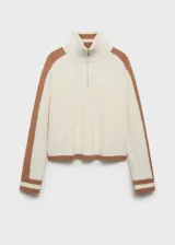Sweater de punto grueso color crema con cuello alto con cierre de cremallera y detalle de rayas marrones en contraste en mangas y ruedo.