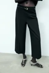 Pantalón culotte color crema, de tiro medio y pierna ancha. Incluye cinturón marrón con hebilla metálica.