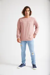 Jean skinny de hombre color negro, ajustado desde la cadera hasta los tobillos, con roturas en las rodillas y logo bordado en el bolsillo trasero.