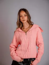 Sweater de punto color rosa con cuello polo y cierre metálico.