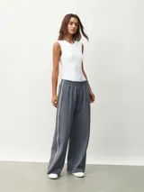Pantalón gris de corte ancho con cintura elástica y rayas verticales blancas a los costados.