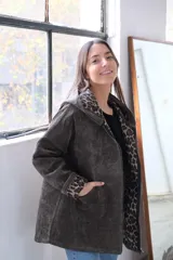 Chaqueta de pana verde con corte amplio, cierre frontal, capucha integrada y bolsillos delanteros. Interior con forro de estampado animal print.