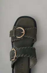 Sandalias de plataforma color verde militar, confeccionadas en cuero, con doble tira ancha con hebillas doradas y suela de goma negra.