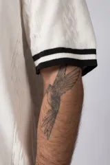 Camisa de tejido de punto color beige, con cuello tipo bowling, manga corta y corte relajado. Cierre frontal con botones.