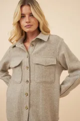 Camisa estilo leñador color beige con textura de espiga, de manga larga con puños abotonados, cuello clásico, cierre frontal con botones y dos bolsillos de parche con solapa abotonada en el pecho.