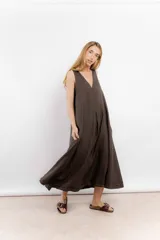 Vestido largo confeccionado en lino de color beige, con escote en V, diseño sin mangas y silueta holgada de caída fluida.