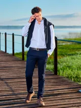 Pantalón de vestir azul marino, de corte slim fit, con bolsillos laterales y traseros. Se ajusta a la cintura con cinturón de cuero marrón.