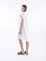 Vestido camisero blanco con corte irregular y mangas cortas.