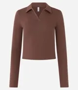 Blusa color crema de rib de algodón, con cuello polo y mangas largas.