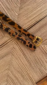 Cinturón de cuero con estampado animal print de leopardo y hebilla dorada cuadrada.