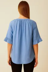 Blusa color blanco de lino y viscosa, con cuello a la base, mangas cortas con volados y cierre frontal con botones.