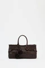 Bolso de mano marrón con cuerpo trenzado y doble asa. Incluye charm extraíble y bolsa interior con cierre fruncido.