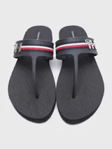 Sandalias de playa color azul marino con tiras de dedo y una banda transversal decorada con las icónicas rayas globales de Tommy Hilfiger y un monograma metálico 'TH'. Cuentan con suela de goma plana y capellada sintética.