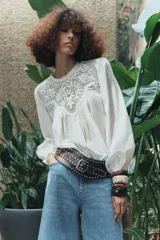Top blanco de algodón con cuello redondo, manga larga abullonada con elástico y detalle de bordados a tono en el canesú.