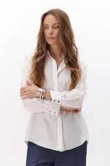Camisa negra de manga larga con cuello clásico y cierre frontal con botones. Presenta costuras decorativas en color blanco.