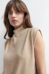 Blusa de lurex sin mangas color beige con tablas en los hombros, diseño holgado.