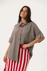 Camisa verde de silueta oversize con cuello camisero y manga 3/4. Tiene bordados de coral y caracol en el frente y botones a tono.