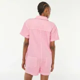 Mono corto color rosa de jean con cuello camisero, cierre frontal con automáticos metálicos, mangas cortas con dobladillo y bolsillos laterales.