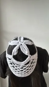 Gorro blanco de crochet con diseño de red y aberturas en la parte superior.