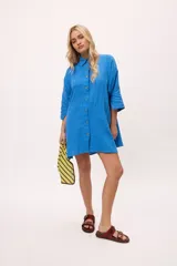 Vestido camisero a rayas verticales de colores pastel, con cuello camisero, cierre frontal con botones y mangas largas.