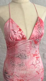 Vestido largo rosado con estampado abstracto en tonos rojos y grises, con breteles finos y espalda descubierta.