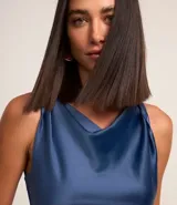 Vestido midi sin mangas confeccionado en tejido con efecto satinado color azul. Posee escote drapeado además de fruncido en el cuerpo.