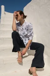 Camisa blanca con estampado floral azul, de lino, con cuello mao, mangas abullonadas al codo y cierre frontal con botones de madera.