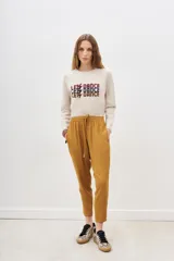Pantalón sporty color ocre, confeccionado en viscosa y elastano, con cintura elástica y tiras regulables, y calce holgado que ajusta al tobillo.