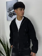 Campera negra de jeans con capucha, cierre frontal con cremallera y corte boxy.